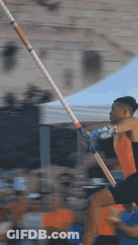 A Man Is Jumping A Pole In Front Of A Crowd Of People GIF