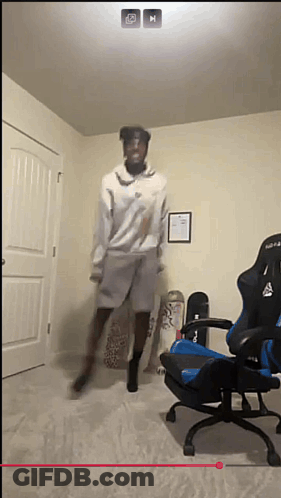 A Man Is Jumping In The Air In A Room With A Chair And Skateboards GIF