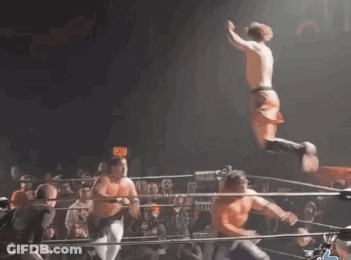 A Man Is Jumping In The Air In A Wrestling Ring With An Exit Sign Behind Him GIF