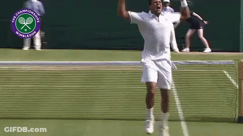 A Man Is Jumping In The Air On A Tennis Court In Front Of A Logo For The Wimbledon Championships GIF