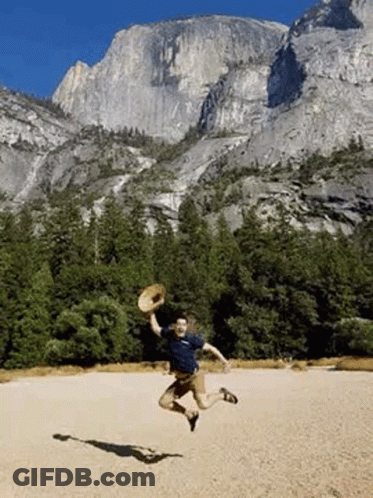 A Man Is Jumping In The Air While Holding A Straw Hat . GIF