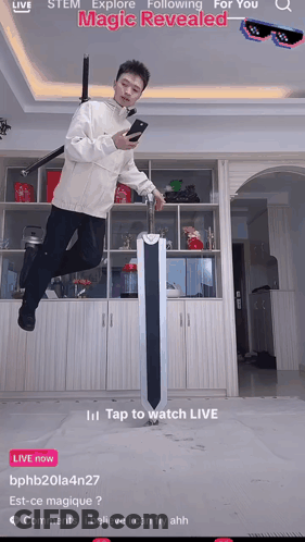A Man Is Jumping In The Air While Holding A Sword And Looking At His Cell Phone GIF