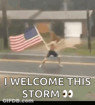 A Man Is Jumping In The Air While Holding An American Flag In Front Of A House . GIF
