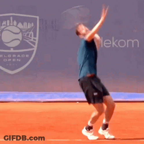 A Man Is Jumping In The Air While Playing Tennis In Front Of A Belgrade Open Sign GIF