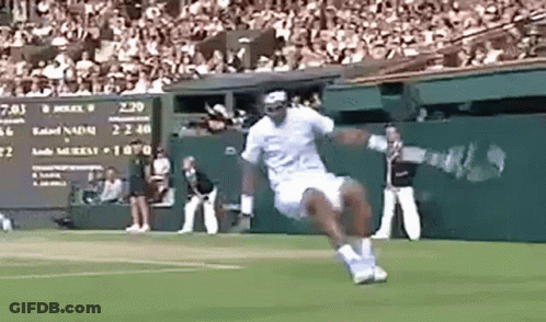 A Man Is Jumping In The Air While Playing Tennis On A Court . GIF