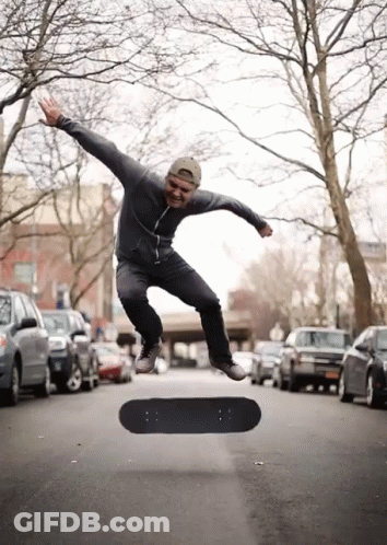A Man Is Jumping In The Air With A Skateboard In The Foreground GIF