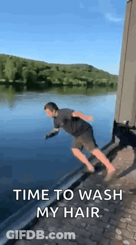A Man Is Jumping Into A Body Of Water With The Words `` Time To Wash My Hair '' . GIF