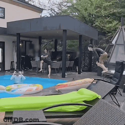 A Man Is Jumping Into A Pool With A Green Float GIF