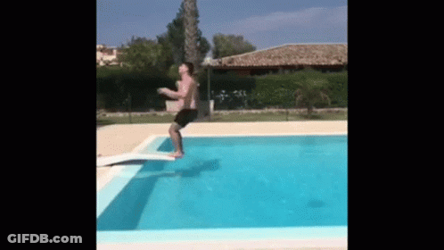 A Man Is Jumping Into A Swimming Pool . GIF