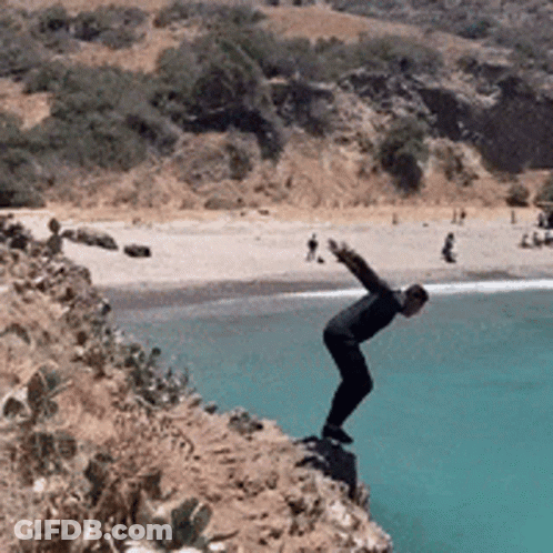 A Man Is Jumping Into The Ocean From A Cliff GIF