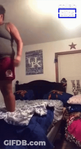 A Man Is Jumping On A Bed With A Uk Poster On The Wall GIF