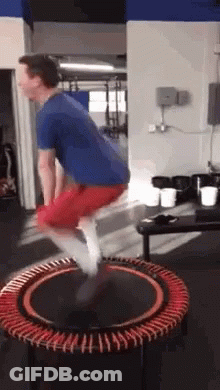 A Man Is Jumping On A Mini Trampoline In A Gym . GIF