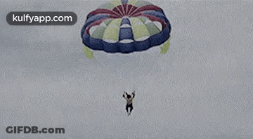 A Man Is Jumping Out Of A Parachute Into The Air . GIF