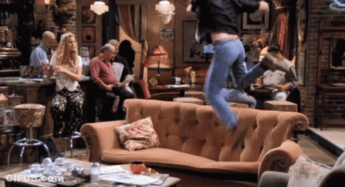 A Man Is Jumping Over A Couch In A Room With A Sign That Says " Valet " On It GIF