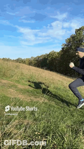 A Man Is Jumping Over A Grassy Hill With Youtube Shorts Written On The Bottom GIF