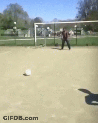 A Man Is Kicking A Soccer Ball In A Field GIF