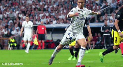 A Man Is Kicking A Soccer Ball On A Field . GIF