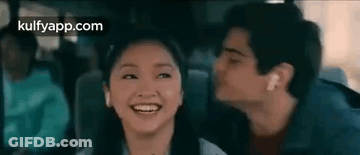 A Man Is Kissing A Woman On The Cheek While They Are Sitting In A Car . GIF