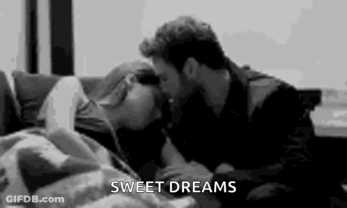A Man Is Kissing A Woman On The Forehead On A Couch . GIF