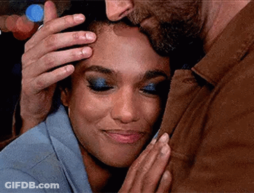A Man Is Kissing A Woman On The Forehead While The Woman Is Smiling . GIF