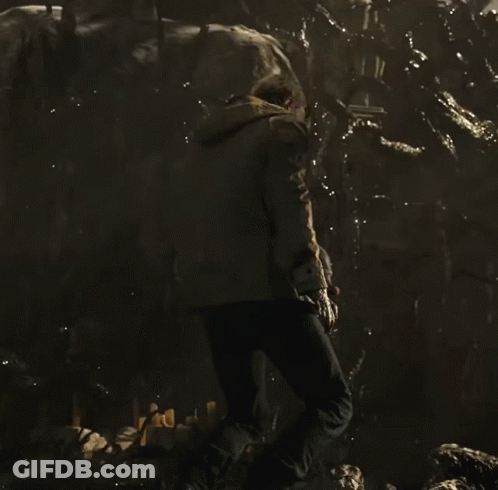 A Man Is Kneeling Down In A Dark Room GIF