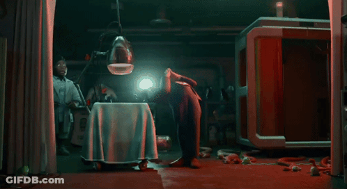 A Man Is Kneeling Down In A Dark Room With A Light Shining On His Head GIF