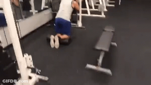 A Man Is Kneeling Down In A Gym With A Bench In The Background . GIF