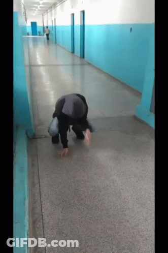 A Man Is Kneeling Down In A Hallway With Blue Walls GIF