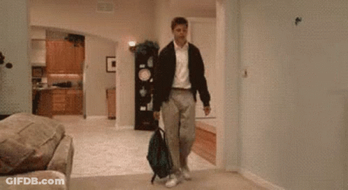 A Man Is Kneeling Down In A Living Room With A Backpack . GIF