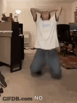 A Man Is Kneeling Down In A Room With His Arms In The Air And The Word No On The Floor . GIF