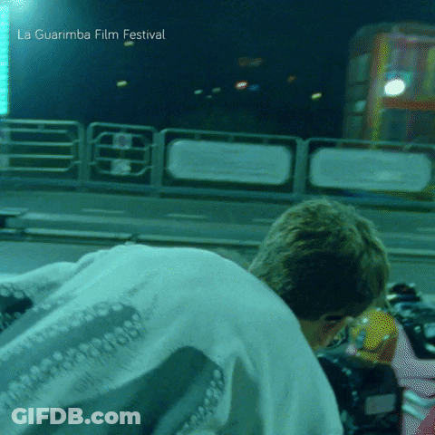 A Man Is Kneeling Down In Front Of A La Guarimba Film Festival Sign GIF