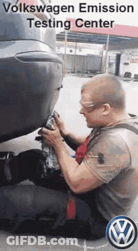 A Man Is Kneeling Down In Front Of A Volkswagen Car . GIF