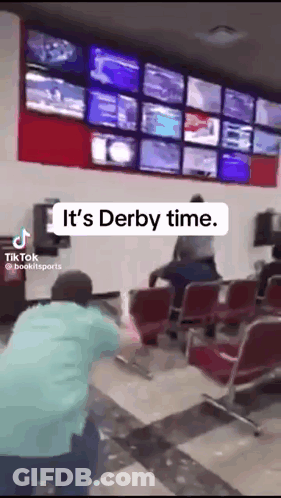 A Man Is Kneeling Down In Front Of A Wall That Says Derby Time GIF