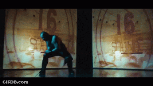 A Man Is Kneeling Down In Front Of A Wall With The Number 16 Written On It GIF
