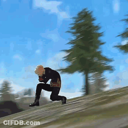 A Man Is Kneeling Down On A Hill With Trees In The Background GIF