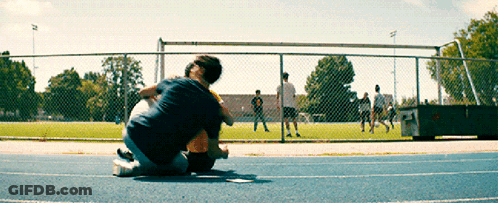 A Man Is Kneeling Down On A Track With A Child In His Lap GIF