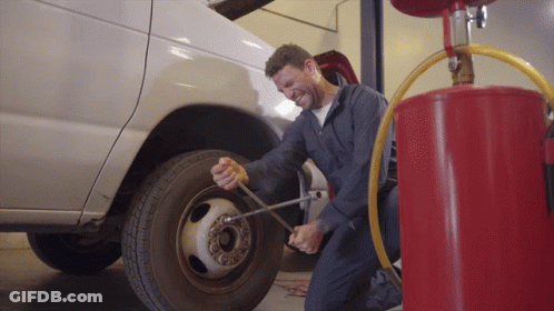 A Man Is Kneeling Down To Change A Tire GIF