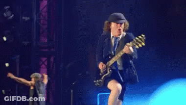 A Man Is Kneeling Down While Playing A Guitar On Stage . GIF
