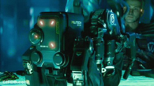 A Man Is Kneeling Next To A Robot That Has The Number 10 On It GIF