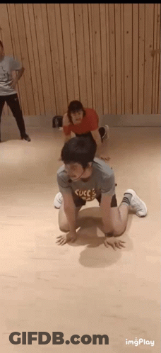 A Man Is Kneeling On The Floor In A Dance Studio While A Woman Stands Behind Him . GIF