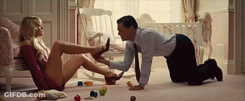 A Man Is Kneeling On The Floor While A Woman Sits In A Chair . GIF