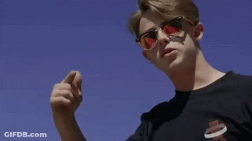 A Man Is Kneeling On The Ground In Front Of A Large Building . GIF