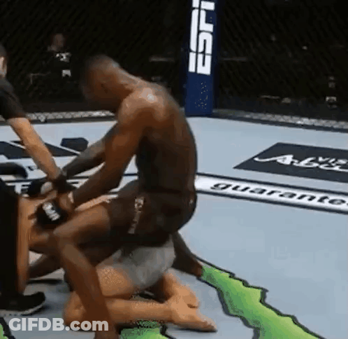 A Man Is Kneeling On Top Of Another Man In A Wrestling Ring . GIF