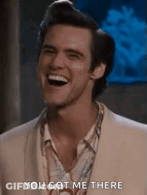 A Man Is Laughing And Saying `` You Got Me There '' While Wearing A Suit . GIF
