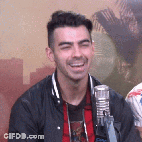 A Man Is Laughing In Front Of A Microphone . GIF