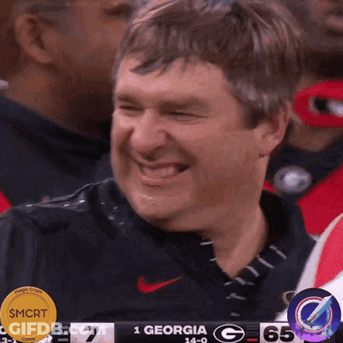A Man Is Laughing In Front Of A Scoreboard That Says Georgia GIF
