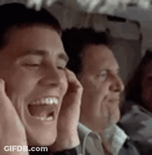 A Man Is Laughing On A Plane While Another Man Covers His Ears . GIF