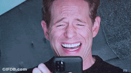 A Man Is Laughing While Looking At His Phone With Fx On The Bottom Right GIF