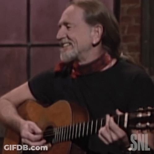 A Man Is Laughing While Playing A Guitar With Snl Written On It GIF