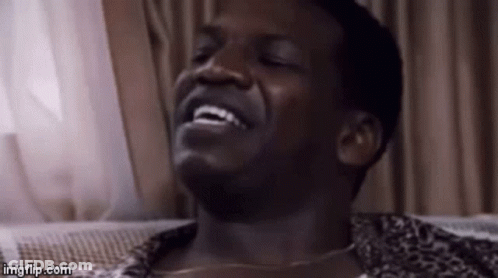 A Man Is Laughing With His Eyes Closed And His Mouth Open . GIF